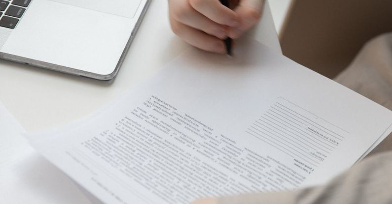 Signature Style - Faceless male worker with paper document near laptop on desk