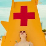 Sunglasses - Shallow Focus Photo of Woman Standing Near Lifeguard Tower