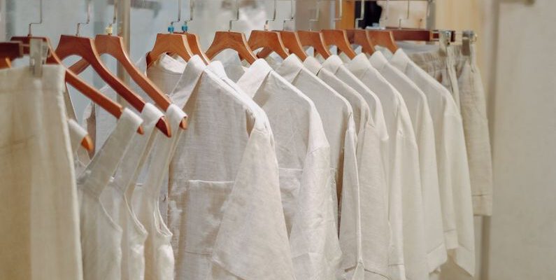 Wardrobe Basics - Clothes in Neutral Colors Hanging on the Racks in a Clothing Store