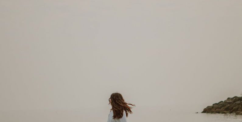 Weekend Style - Anonymous tourist admiring sea from stone in misty weather