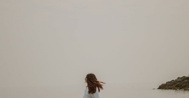 Weekend Style - Anonymous tourist admiring sea from stone in misty weather