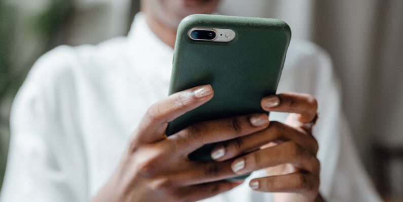 Casual Look - Black woman messaging on modern cellphone