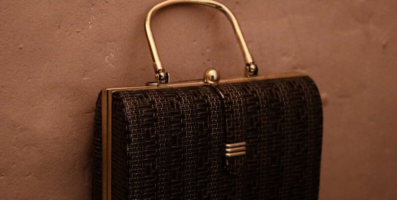 Vintage Trend - Vintage bag with golden handle placed on reflecting surface as accessory for garment