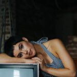 Vintage Designer - Peaceful female wearing overall lying on vintage TV set sitting on seethe in tailor workshop for sale