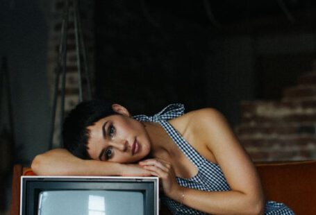 Vintage Designer - Peaceful female wearing overall lying on vintage TV set sitting on seethe in tailor workshop for sale