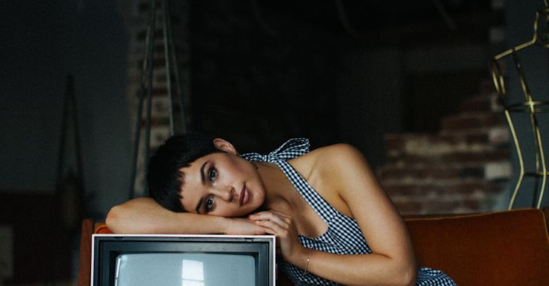 Vintage Designer - Peaceful female wearing overall lying on vintage TV set sitting on seethe in tailor workshop for sale